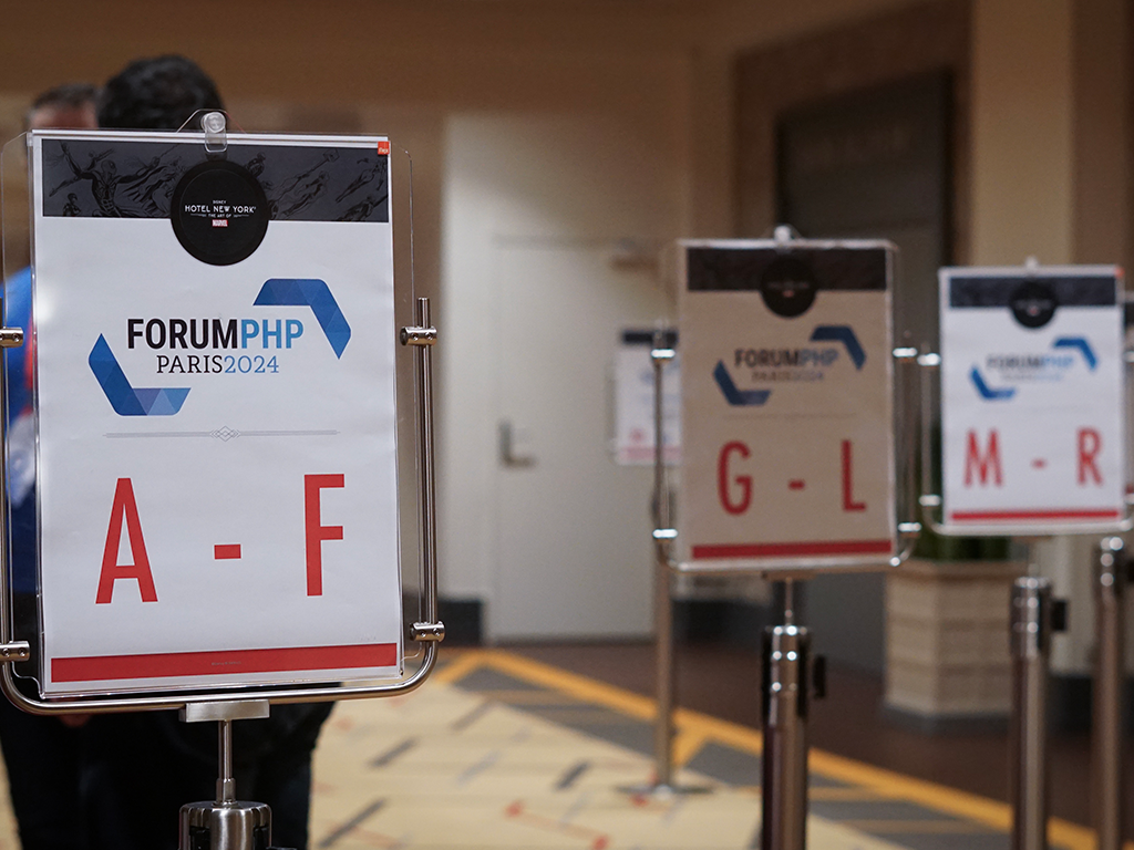Des panneaux d'affichage orientent le public en fonction du nom de famille à l'accueil badge du Forum PHP 2024