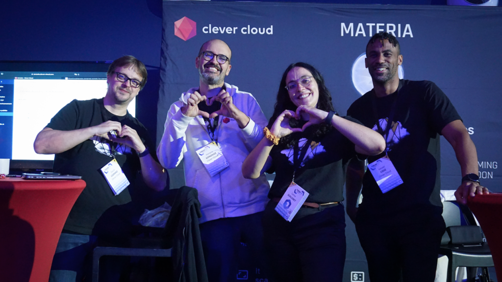 L'équipe Clever Cloud, sponsor de l'événement, sur son stand au Forum PHP 2024. elle fait des coeurs avec les mains.